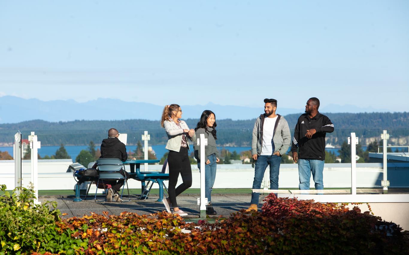 Students socializing on a rooftop patio under a blue sky. 