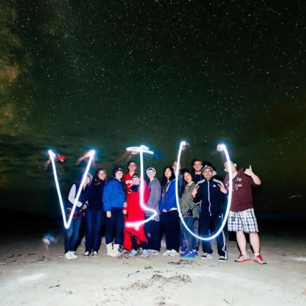 A group of students with light-up tubes that spell out VIU.