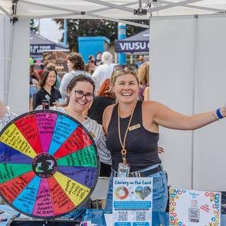 Library staff invite students to their booth with a quiz wheel