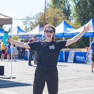 a student spreads her arms wide in welcome in front of the RockVIU booths