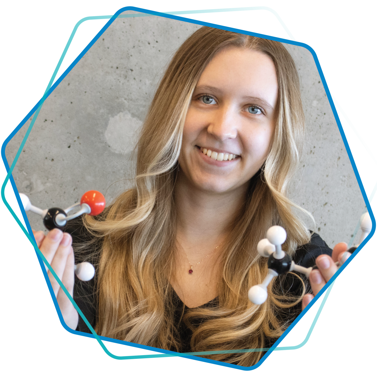 A smiling young woman holding models of cellular structures.