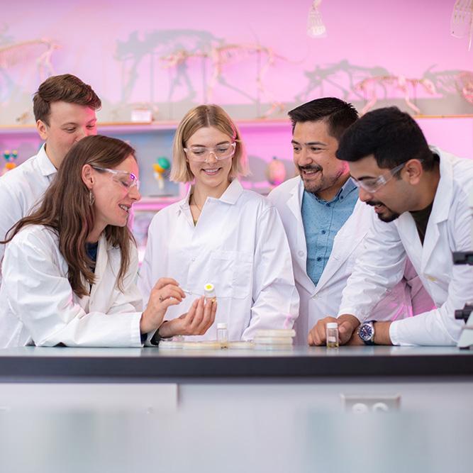 Group of people in lab coats looking at something together. 