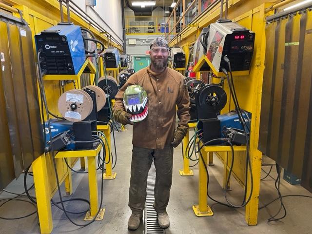 Smiling man in a welding shop.