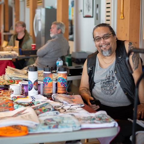 Indigenous man selling colourful items at a market.